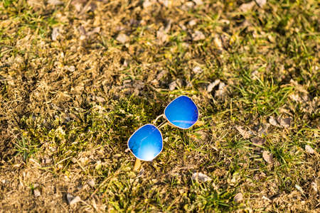 Classic sunglasses model with blue lenses shoot outside in nature in a sunny day closeup . Selective focusの写真素材