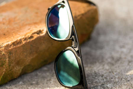 Sunglasses model with blue green lenses shoot outside in a summer day closeup . Selective focusの写真素材