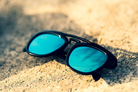 Sunglasses model with blue green lenses shoot outside in a summer day closeup . Selective focus