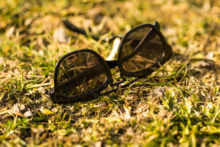 Sunglasses with black lenses and black frame shoot outside in nature in a sunny day closeup . Selective focusの写真素材