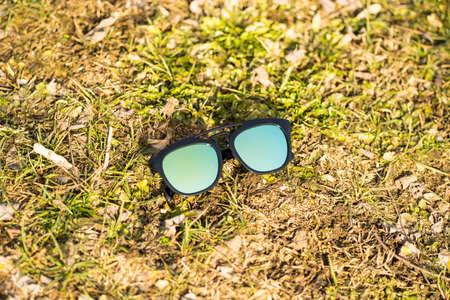 Sunglasses model with blue lenses shoot outside on the grass in a sunny day closeup . Selective focusの写真素材