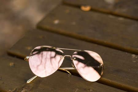 Aviator Sunglasses model with big pink lenses reflecting the sun in a summer day closeup . Selective focusの写真素材