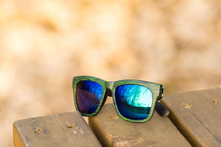 Classic sunglasses model with blue reflecting lenses and green frame in a summer day closeup . Selective focusの写真素材