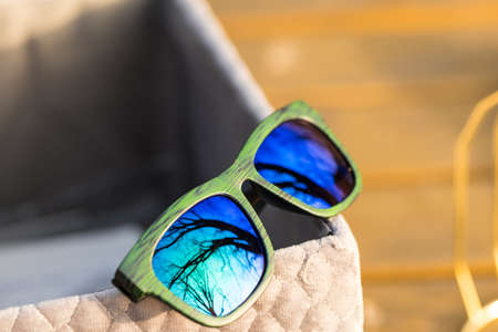 Classic sunglasses model with blue reflecting lenses and green frame in a summer day closeup . Selective focusの写真素材