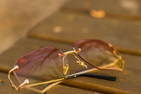 Futuristic sunglasses rimless design with pink lenses and golden frame shoot outside in a sunny day. Selective Focusの写真素材