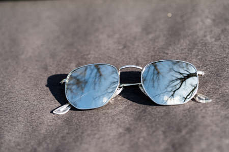 Classic sunglasses model with silver round golden lenses shoot outside in a summer day closeup . Selective focusの写真素材
