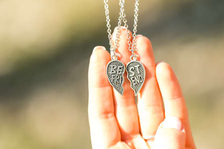 Set of best friends heart necklace shoot outside in a summer day closeup. Selective Focusの写真素材