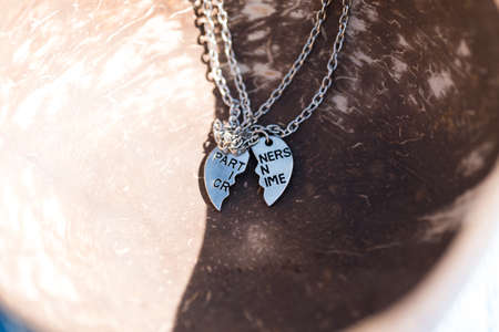 Partners in crime pendant necklace for lovers or best friends. Shoot outside in sunny day closeup. Selective Focusの写真素材