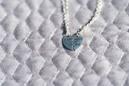 Partners in crime pendant necklace for lovers or best friends. Shoot outside in sunny day closeup. Selective Focusの写真素材