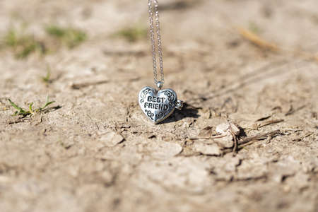 Pendant Best Friend heart necklace shoot outside in a summer day closeup. Selective Focusの写真素材