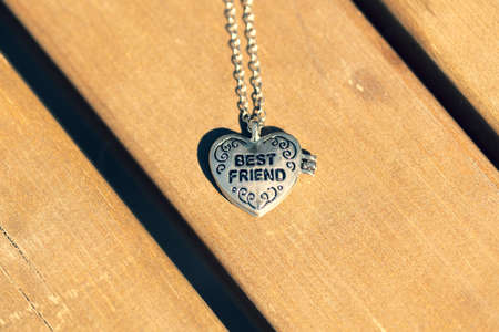 Pendant Best Friend heart necklace shoot outside in a summer day closeup. Selective Focus