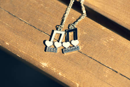 Pendant set of best friends two colors musical notes necklace shoot outside in a sunny day closeup. Selective Focusの写真素材