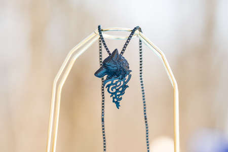 Pendant wolf head necklace black color shoot outside in a sunny day closeup. Selective Focusの写真素材