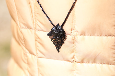 Pendant wolf head necklace black color shoot outside in a sunny day closeup. Selective Focusの写真素材