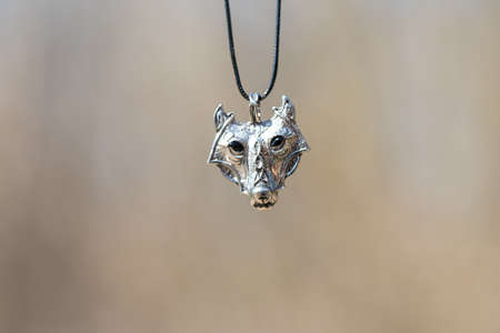 Pendant wolf head necklace silver color stainless steel shoot outside in a summer day closeup. Selective Focusの写真素材