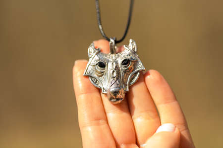 Pendant wolf head necklace silver color stainless steel shoot outside in a summer day closeup. Selective Focusの写真素材