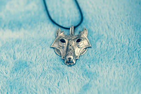Pendant wolf head necklace silver color stainless steel shoot outside in a summer day closeup. Selective Focusの写真素材
