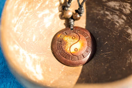 Yin Yang pendant necklace brown color handmade shoot outside in a sunny day closeup. Selective Focusの写真素材
