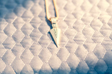 Pendant arrow necklace golden color shoot in a sunny day outside closeup. Selective Focusの写真素材