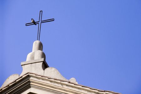 Bird perched on the cross adorning church roofの写真素材