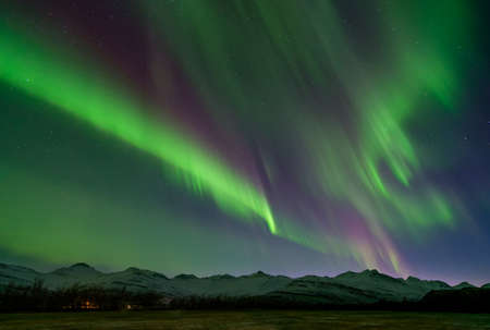 Awesome green and purple aurora over mountains covered with snow, in Iceland, in November 2017.の写真素材