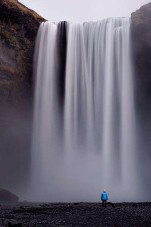 Long exposure of person staring at Skogafoss waterfall in Icelandの写真素材