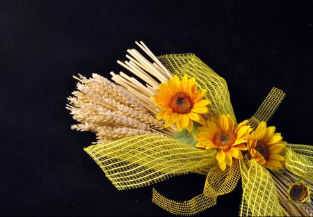 Decoration consists of stalks of wheat and sunflowers on a black background.の写真素材