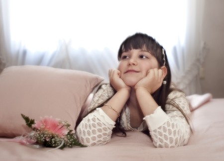 Dreamy-eyed child lying in bed with parentsの写真素材