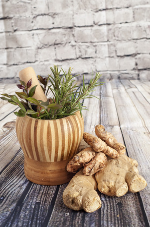 Ginger, turmeric and herbs on a wooden boardの写真素材