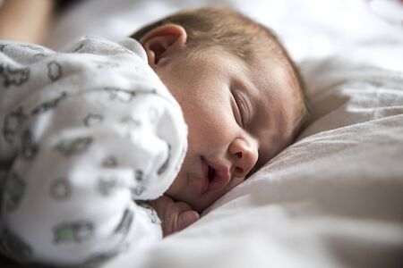 Newborn sleeping peacefully in white bed