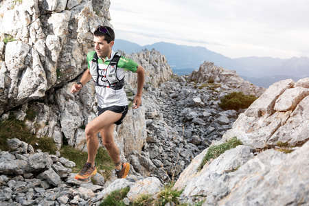 Athlete Runner Runs Rocks In Mountain. Sport Concept