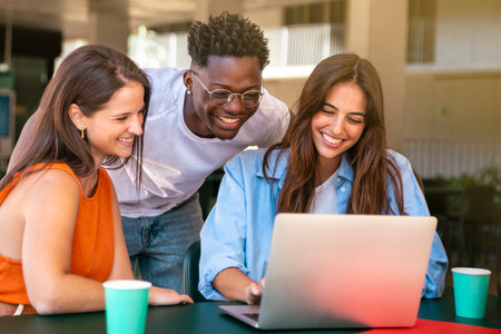 Group of happy friends students sitting in a cafe bar looking at laptopの写真素材