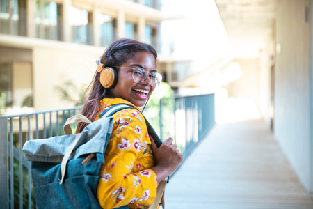 Happy young woman with headphones and backpack looking at camera in the university - Portrait of smiling student looking at camera with bakcpack.の写真素材