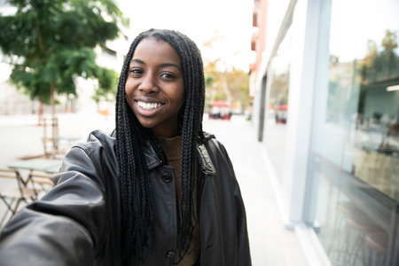 happy young woman smiling taking a selfie portrait in the city - portrait of young afro american woman taking a selfie outdoorの写真素材