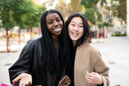 portrait of two multiracial woman looking at camera. A couple of happy females standing outdoors in the city. fashion, lifestyle conceptの写真素材