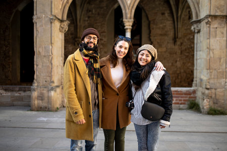 portrait of multiracial group of friends looking at camera. Three happy young adults standing in an ancient city. Holidays, friendship, cheerful conceptの写真素材