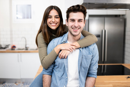 portrait of smiling young couple in the kitchen at home. Handsome man and beautiful woman standing together ans looking at camera. Lifestyle concept.の写真素材