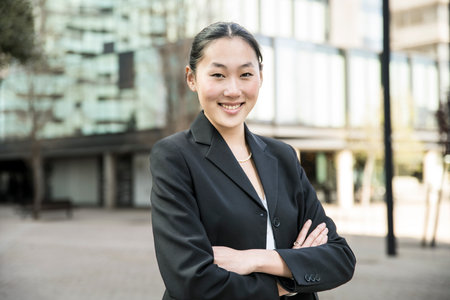 Portrait of a female executive looking confident with arms crossed. Businesswoman smiling and standing sideways in the street.の写真素材