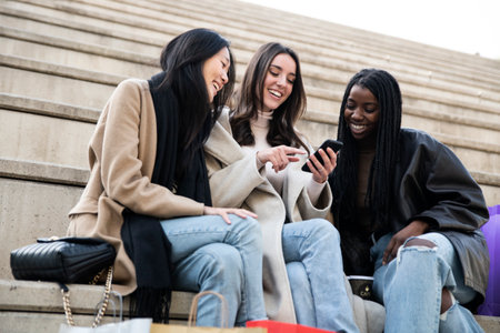 three multiracial happy beautiful friends looking at phone in the street . Cheerful friends having fun together outdoors. Friendship conceptの写真素材