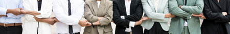 Panoramic close up of an executive team standing in a line holding hands. Businesspeople bonding together standing. Teamwork conceptの写真素材