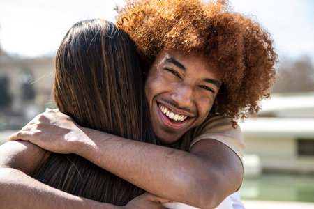 Close up of a young happy man hugging a woman with straight hair. Lovely guy smiling while embracing a lady at outdoors.の写真素材