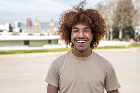 Young handsome guy smiling relaxed and looking at camera in the street. Confident happy man laughing and staring at camera standing outdoors.の写真素材