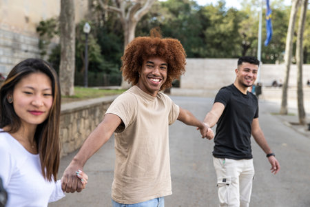 Three diverse and confident friends holding hands together. Multiracial group of people smiling and holding hands in a line.の写真素材