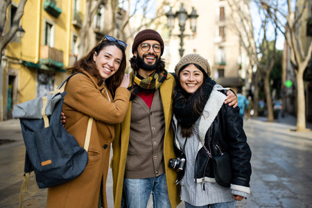 Portrait of three happy tourists standing on the street and looking at camera. Group of travelers enjoying a trip in Barcelonaの写真素材