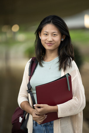 Handsome satisfied student holding a notebook looking at camera.Relaxed and happy woman standing...