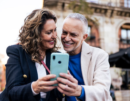 Smiling mid adult tourists travelling together taking a selfie in the street. Lovely senior friends taking a picture together while traveling.の写真素材