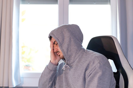 <p>sad young man with a headache sitting alone in the office chair about to cry</p>の写真素材