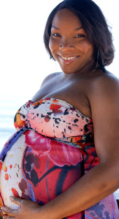 A happy pregnant woman smiling and holding her bellyの写真素材