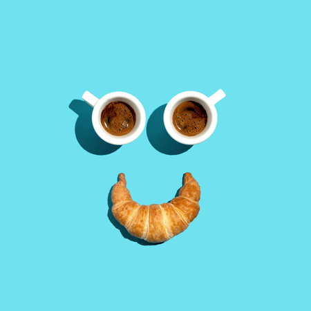 Coffee and croissant breakfast in a minimalist art setting against a blue backgroundの写真素材