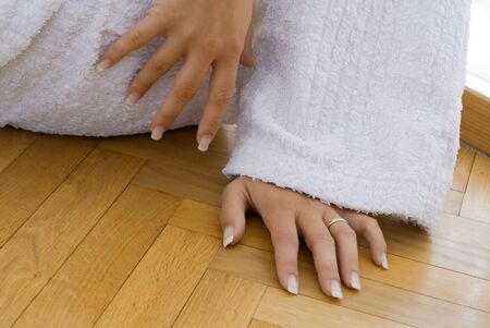 young and cute blond woman wearing a white bathrobe sitting down on the floor of her bathroom